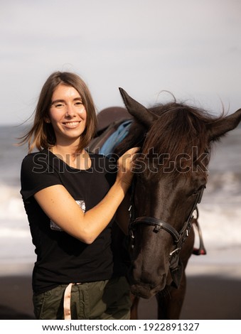 Portrait of happy woman and brown horse. Young Caucasian woman hugging horse. Romantic concept. Love to animals. Nature concept. Bali, Indonesia
