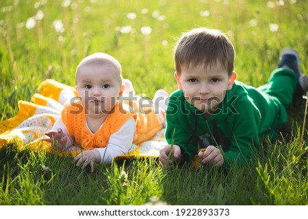 Picture of a brother and sister having fun in the park,lying on the green grass.