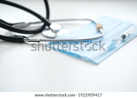 A stethoscope, a medical mask and a syringe for injection lies on a white background, close-up. Concept medicine