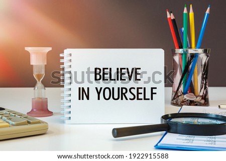 Believe in yourself is written on a notepad on an office desk with office accessories. Royalty-Free Stock Photo #1922915588