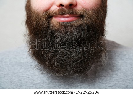 Portrait. The man with the thick beard smiles. The bearded man laughs. Lips, nose, mouth of a bearded man, close-up. A well-groomed, thick, beautiful beard. Close-up.