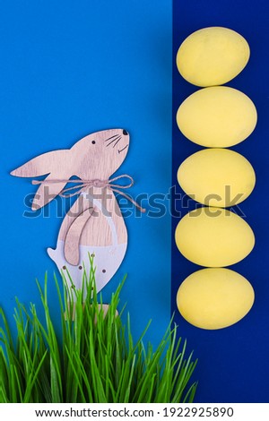 Greeting Easter card concept. Pastel yellow easter eggs and rabbit toy, top view. High quality photo