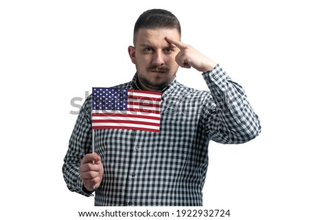White guy holding a flag of United States and a finger touches the temple on the head isolated on a white background.