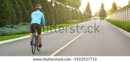 Website header of Cropped shot of a man riding mountain bike in park during sunset, cycling outdoors on a summer day