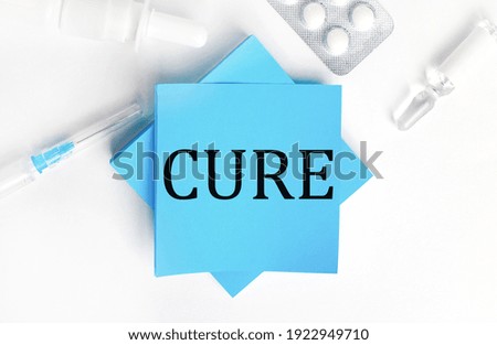 On a white background, a syringe, ampoule, pills, a vial of medicine and light blue stickers with the inscription CURE. Medical concept