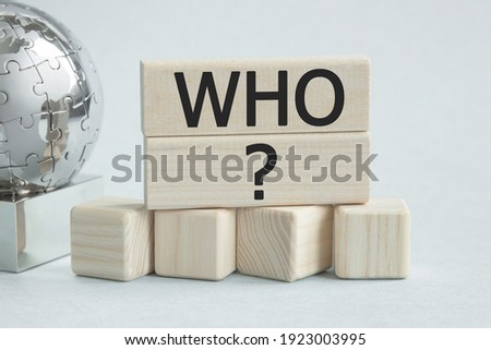 Text WHO. Globe and wooden cubes on a gray background. The concept of world business, marketing, finance.