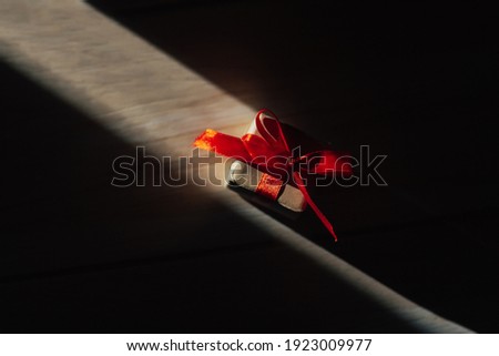 Little gift box with red bow on the light on sun with shadows.