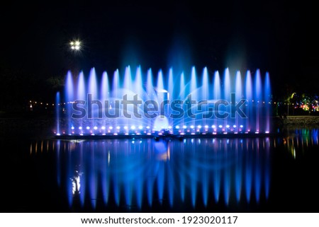 A dancing fountain or a fountain that is formed by controlling the ups and downs and has a light tone bright blue .  And the color reflecting on the water. Royalty-Free Stock Photo #1923020117