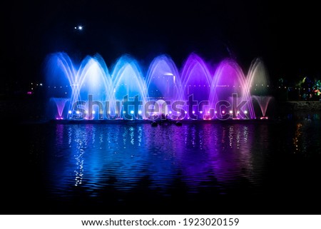 A dancing fountain, or fountain, formed by a controlled ascending and descending rainbow-like lights.  And the color reflecting on the water. Royalty-Free Stock Photo #1923020159