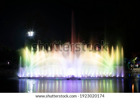 A dancing fountain or a fountain that is formed by controlling the ups and downs and has a light tone green bright.  And the color reflecting on the water. Royalty-Free Stock Photo #1923020174