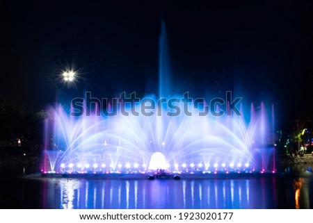 A dancing fountain or a fountain that is formed by controlling the ups and downs and has a light tone bright blue .  And the color reflecting on the water. Royalty-Free Stock Photo #1923020177