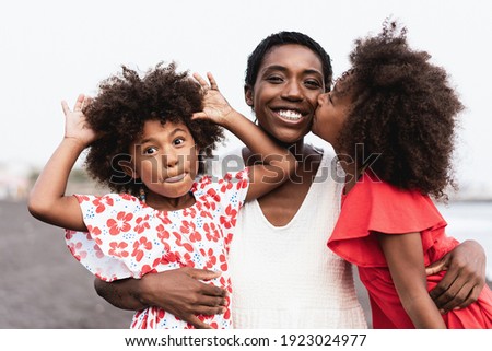 Happy african sister twins kissing mother on the beach - Focus on mother face Royalty-Free Stock Photo #1923024977