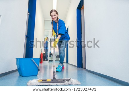 Cleaning lady mopping the floor in an office building, low shot Royalty-Free Stock Photo #1923027491