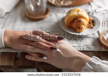 Man and woman holding hands together at restaurant, closeup