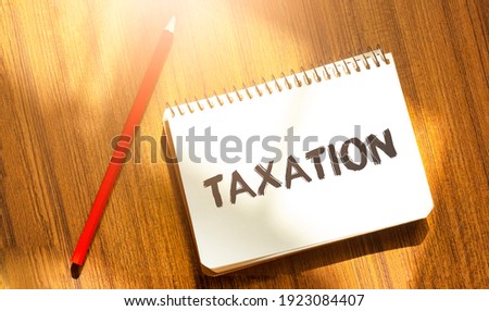 notebook and pen on a wood table, copy space for text, inscription TAXATION on crumpled yellow paper, work place, brainstorming