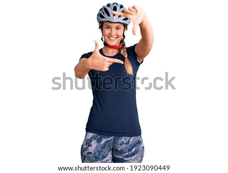 Beautiful caucasian woman wearing bike helmet smiling making frame with hands and fingers with happy face. creativity and photography concept. 