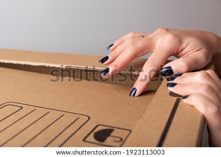 Feminine hands divide cut part of carton box that will offer entrance to light rays through tissue paper window with copy space