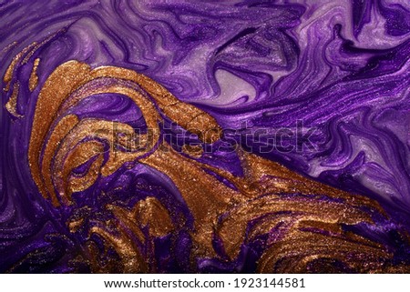 Beautiful purple and gold stains of liquid nail polish,fluid art technique.Shimmer marble background.Liquid stripy paint texture.Nail laquer flow modern backdrop.Minimalistic concept.Copy space.