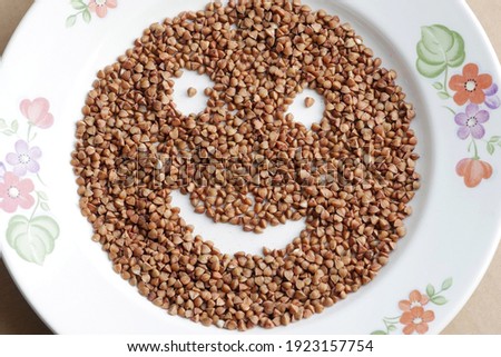 Preparing buckwheat cereal for cooking, funny onion in a plate. Smile of cereal on a white plate, close-up, top view