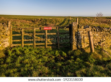 Gate with 'Private' sign and barbed wire preventing access from a public bridleway north of Hadrian's Wall to a track across open farm land in Northumberland, England