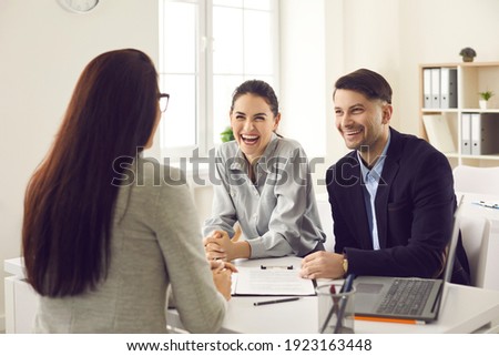 Married couple in the office at a consultation meeting in a friendly atmosphere talking to the bank manager. Husband and wife negotiate the first purchase of a house or take a loan. Royalty-Free Stock Photo #1923163448