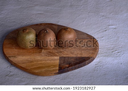 Group of kiwis on wooden plank, Three units, stone floor, front view