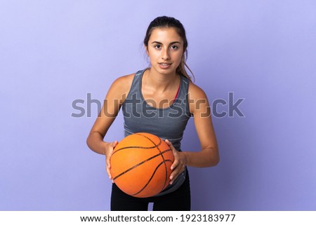 Young hispanic woman over isolated purple background playing basketball