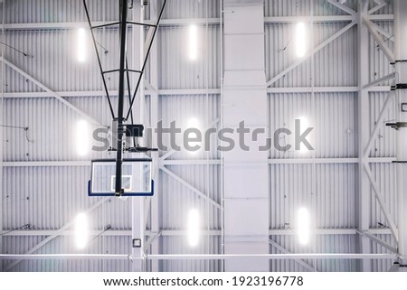 Bottom view of portable basketball support frames with lifting system on the celling of court. The court can be used for tennis and badminton as well. Detail light background and structure texture.