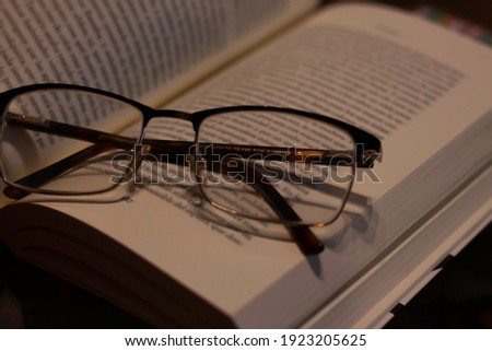 A glasses over a opened book on a wooden table. Time for reading and literature concept.