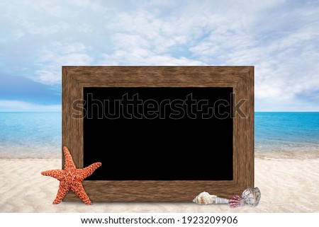 Summer vacation wooden picture frame with copy space on blurred sandy beach, blue sea and sky background with starfish and seashells.