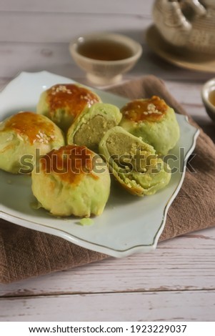 unfocus picture of Some delicious bakpia are put on white plate, bakpia is a baked flour roll filled with green beans and sugar from Indonesia served with some tea. Isolated. Top view