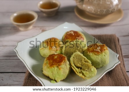 unfocus picture of Some delicious bakpia are put on white plate, bakpia is a baked flour roll filled with green beans and sugar from Indonesia served with some tea. Isolated. Top view