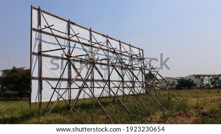 Wooden structure of the billboard. The weathered wood back supports a white billboard on a lawn and sky background with a copy area. Selective focus