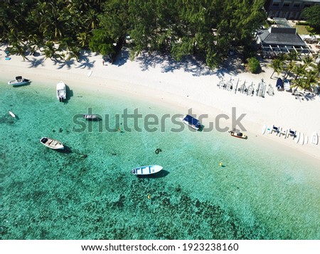 Aerial picture of Le Morne tranquil beach in Mauritius Island. Beautiful transparent lagoon in the Indian Ocean, shot from above. Boats sailing in turquoise waters, soft sand and resorts in the coast.