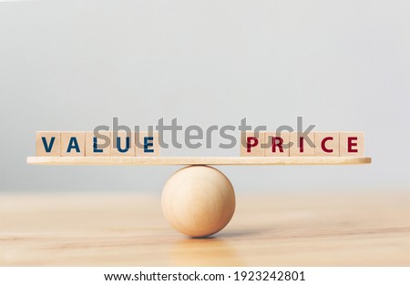 Wooden seesaw scale empty on wooden sphere on wood table with wording VALUE and PRICE balancing
