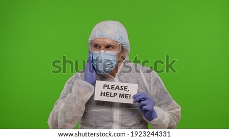 Medical worker doctor in PPE suit with text inscription slogan on paper - Please, Help Me. Isolated on chroma key background waiting for vaccination injection against coronavirus covid-19 pandemic