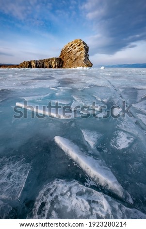 Lake Baikal, covered with ice. A popular destination for tourists and photographers. Winter landscape. Russia. Beautiful blue ice with cracks, snow blocks on a frosty March day.