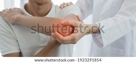 Female physiotherapists provide assistance to male patients with elbow injuries examine patients in rehabilitation centers. Rehabilitation physiotherapy concept. Royalty-Free Stock Photo #1923291854