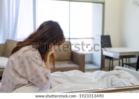 View of woman patient sitting on hospital bed and closing her face. Woman Patient serious about her health problem. Royalty-Free Stock Photo #1923313490