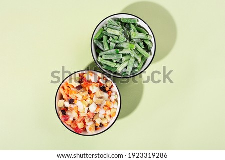 frozen vegetable mixture in a bowl on a green background, top view, hard light, shadows Royalty-Free Stock Photo #1923319286