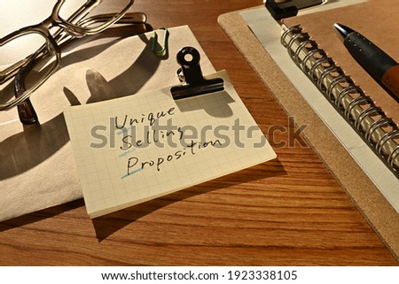 There is a piece of paper with the word Unique Selling Proposition on the desk with a glasses and clipboard.
