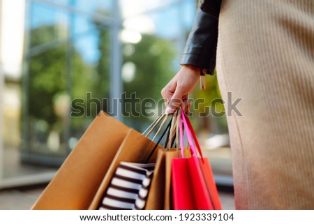 Shopping bags in the woman hands. Young woman after shopping on the city street. The joy of consumption, Purchases, black friday, discounts, sale concept. Royalty-Free Stock Photo #1923339104