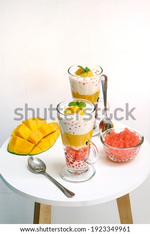 Selective focus of mango sago is traditional asian food, made from mango, sago, jelly mango with evaporate milk on glass , sweet and tasty