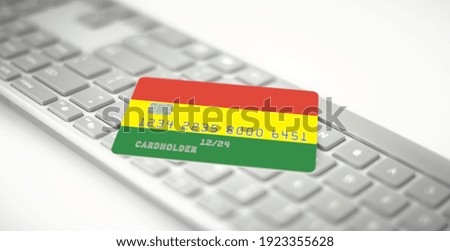 Bank card depicting flag of Bolivia on computer keyboard. Fictional numbers