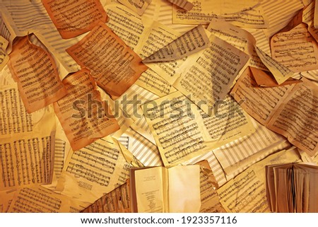 Music notes background. old sheets of sheet music on the wall                             Royalty-Free Stock Photo #1923357116