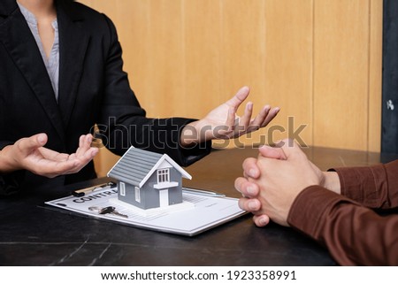A real estate agent with a House model is talking to clients about buying home insurance. Home insurance concept.