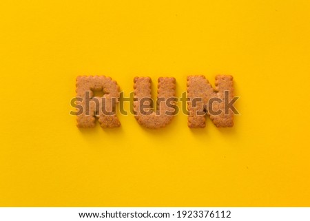 Word Run in the middle of the picture made of tasty crunchy cookies in form of English alphabet letters, textured bright yellow background, health, dieting and medical concept. Copy space, big letters