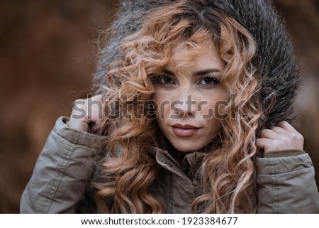 Portrait of young woman with curly hair in winter jacket. Copy space