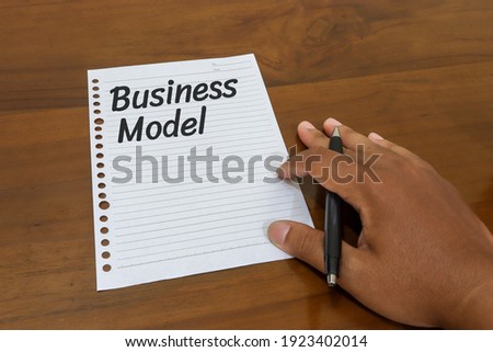 Business Model, text words typography written on loose leaf paper with pen against wooden background. Finance and business concept
