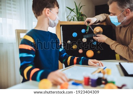 Happy school boy and his father making a solar system for a school science project at home